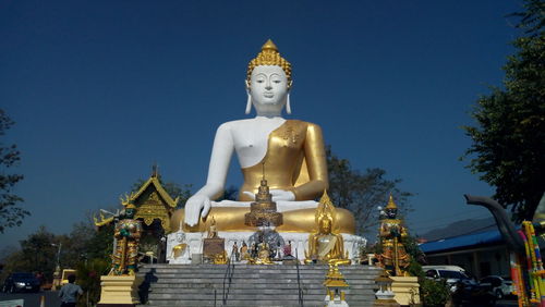 Statue outside temple against building against sky