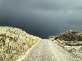 Road amidst land against sky