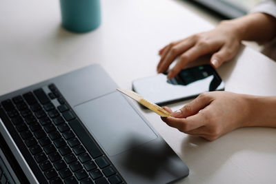 Close up woman hands holding credit card and smartphone paying online, using banking service,