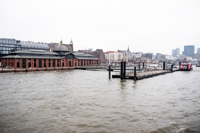 Bridge over river by buildings against clear sky