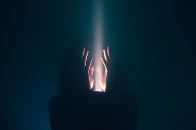 Close-up of silhouette hand against illuminated light