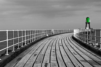 Railing by bridge against sky