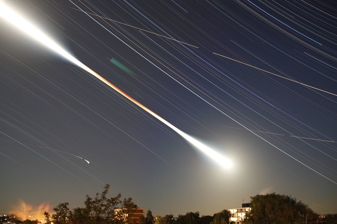 LOW ANGLE VIEW OF STAR TRAILS AGAINST SKY AT NIGHT