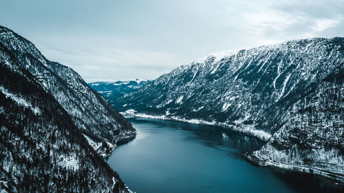 Scenic view of lake by snowcapped mountains against sky