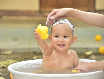 Shirtless baby boy sitting in tub