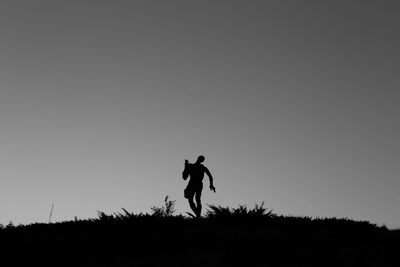 Silhouette man standing on field against clear sky during dusk