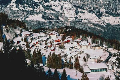 High angle view of snow covered trees and houses against mountain
