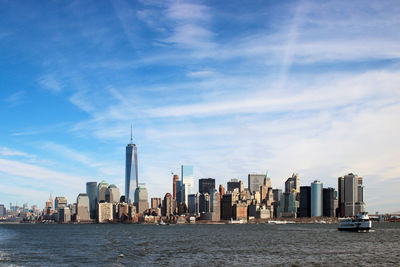 Sea by modern buildings against sky in city