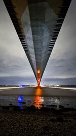 Illuminated bridge over sea against sky during sunset
