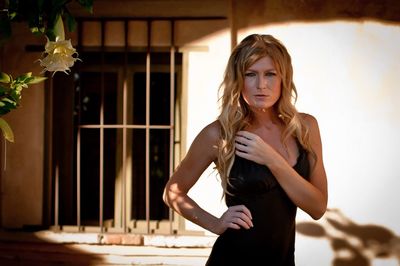 Portrait of young beautiful woman with long blond hair while standing outside house on sunny day