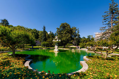 Fountain in park by lake against clear sky