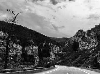 Road by trees and mountains against sky