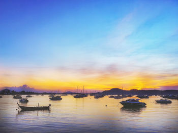 Sailboats in sea at sunset