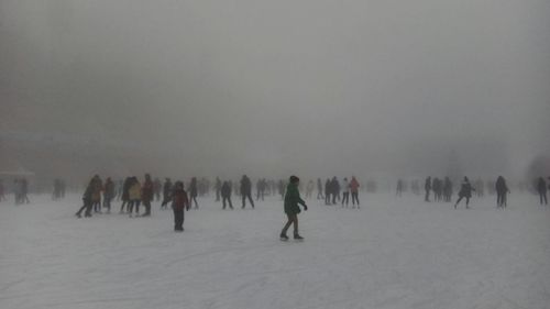 People on snow covered landscape against sky