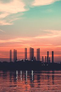 Scenic view of sea by buildings against sky during sunset