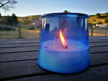 Close-up of burning candle against blue sky