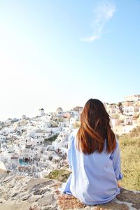 Rear view of woman looking at cityscape against sky