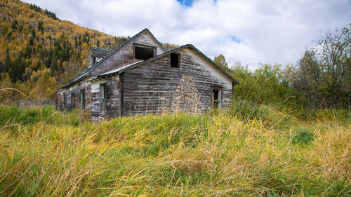 Abandoned house on field against sky