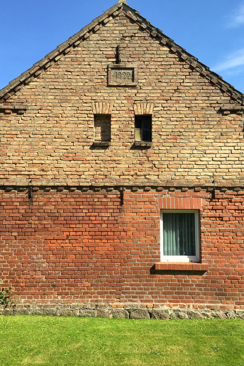 building exterior, architecture, built structure, brick wall, low angle view, window, house, stone wall, old, sky, brick, wall - building feature, blue, day, residential structure, outdoors, clear sky, no people, sunlight, wall