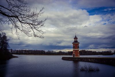 Lighthouse amidst buildings against sky during winter