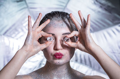 Close-up portrait of young woman holding diamonds against umbrella 