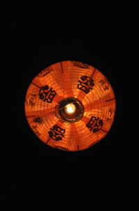 Low angle view of illuminated lamp against black background