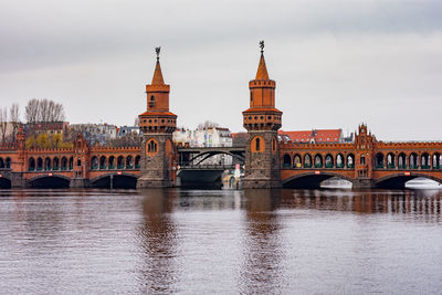 Arch bridge over river against buildings in city