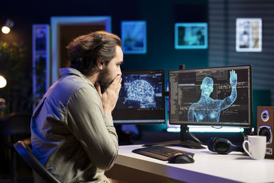 Side view of man using laptop at office