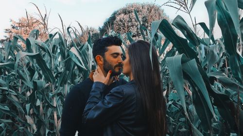 Side view of young couple standing against plants