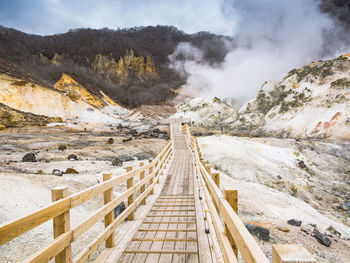 Panoramic view of footbridge over mountains against sky