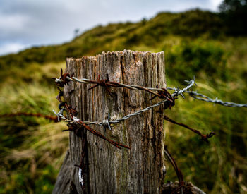 Close-up of barbed wire fence on field