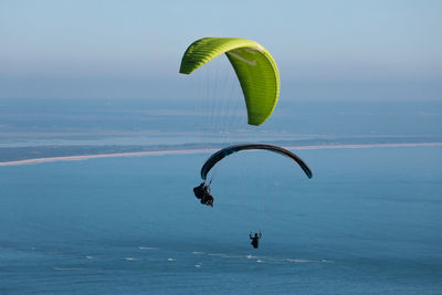 Low angle view of person paragliding against sky