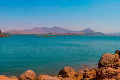 Scenic view of sea and mountains against blue sky