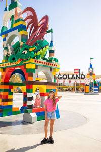 Full length portrait of woman standing against multi colored building