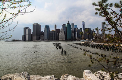 Modern buildings by lake against sky in city