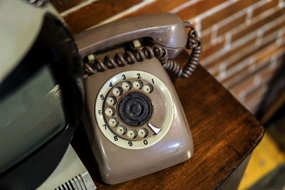 Vintage telephone on table against brick wall