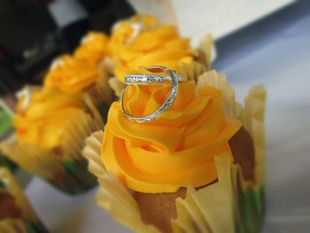 Close-up of wedding rings on fresh yellow cupcake