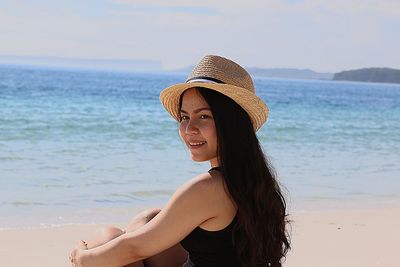 Portrait of smiling young woman sitting on shore at beach