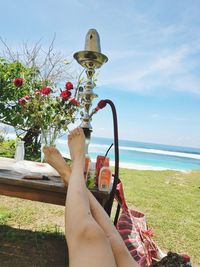 Low section of woman holding umbrella against sea