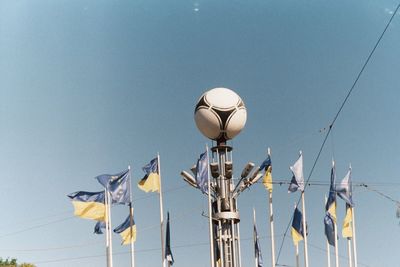 Low angle view of sculpture and flags against clear sky