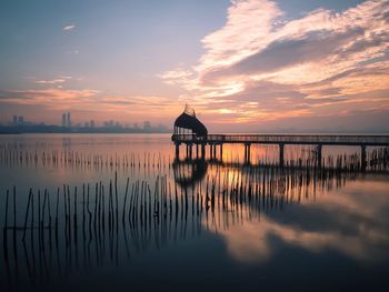 Silhouette pier over sea against sky during sunset