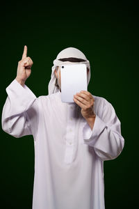 Midsection of doctor holding dentures while standing against black background
