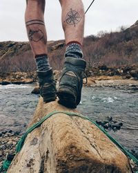 Low section of man balancing on log over river