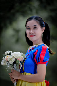 Portrait of young woman standing against plants