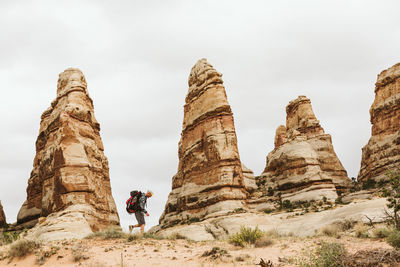 Male hiker walks next to red rocks towers in the desert of utah