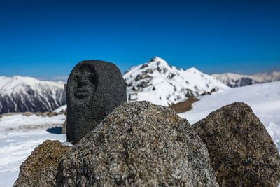 Close-up of snow on rock against blue sky