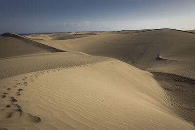 Sand dunes in desert against sky