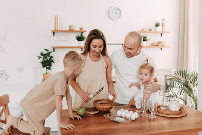 Happy big family of mom dad two kids cooking together and having fun in the kitchen at home