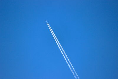 Low angle view of vapor trail against blue sky