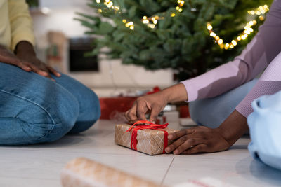 African couple wrapping xmas presents together, preparing for new years eve celebration at home